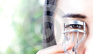 A woman is using eyelash curler