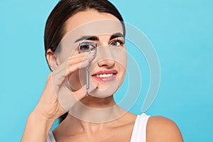 Woman using eyelash curler on  background