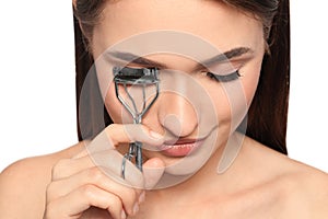 Woman using eyelash curler on background, closeup