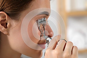 Woman using eyelash curler, closeup. Space for text
