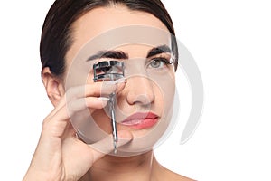 Woman using eyelash curler on white background