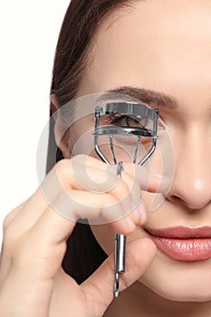 Woman using eyelash curler on white background, closeup