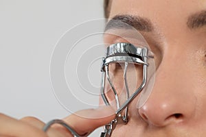 Woman using eyelash curler on white background, closeup. Space for text