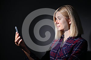 Woman using facial detection system of modern smartphone on dark background