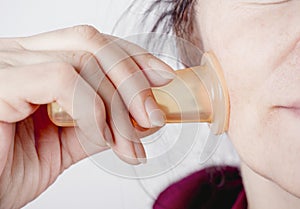 Woman using facial silicone cup cupping tool in home bathroom. photo