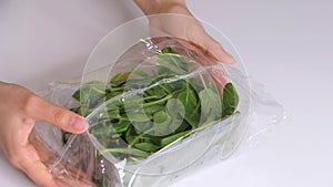 Woman using food film for food storage on a white table. Roll of transparent polyethylene food film for packing products