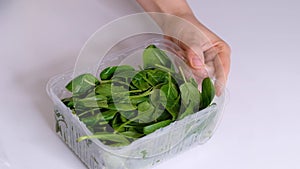 Woman using food film for food storage on a white table. Roll of transparent polyethylene food film for packing products