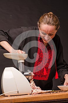 Woman using grinder for preparation of minced meat in kitchen