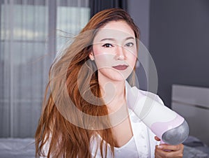 Woman using hair dryer in bedroom