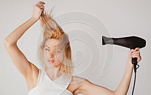 Woman using a hair dryer, hairdryer. Young woman with drying hair with hair dry machine.