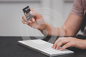 Woman is using a hand typing keyboard and uses a modern credit card by laptop or smartphone