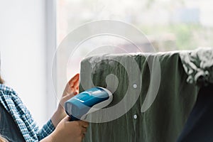 Woman Using Handheld Steamer on a Green Garment at Home During Daytime