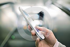 Woman using her cell phone in Subway on escalator