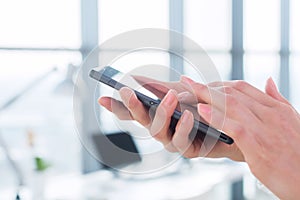 Woman using her digital device, reading news, sending sms, surfing internet, blogging and apps in office, close-up photo