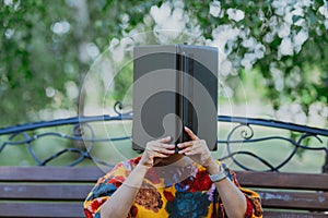 Woman using her laptop as an open book, covering her face