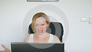A woman using her laptop, sitting at the table, angry and irritated, swears. Human emotions. internet addiction concept.