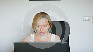 A woman using her laptop, sitting at the table, angry and irritated, swears. Human emotions. internet addiction concept.