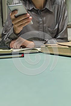 Woman using her mobile during office work.Notebook, business documents, pen on the desk.Empty space.Vertical image