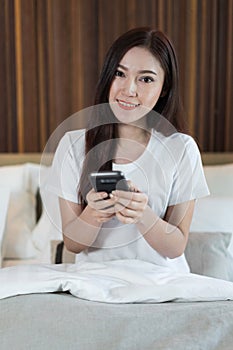 Woman using her smartphone on bed