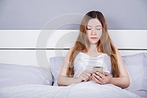 Woman using her smartphone on bed