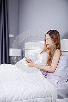 Woman using her smartphone on bed