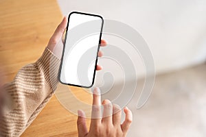 A woman using her smartphone indoors, a white-screen smartphone mockup in a woman's hand