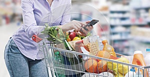 Woman using her smartphone at the supermarket