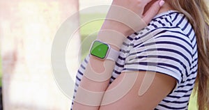 Woman using her smartwatch touchscreen with greenscreen.