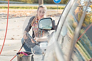 Woman using high pressure nozzle to clean her car