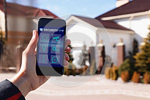 Woman using home security app on smartphone outdoors, closeup