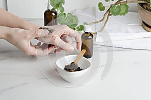 Woman using homemade coffee scrub for pilling, tasting on her hands before applying on face