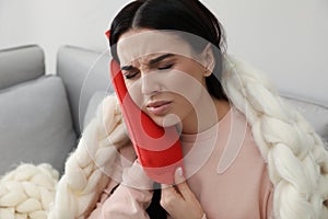 Woman using hot water bottle to relieve pain at home photo