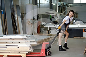 Woman using hydraulic trolley in carpenter workshop