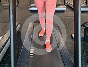 Woman using incline threadmill in modern gym. Incline threadmills are used to simulate uphill walking