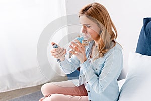 Woman using inhaler with spacer in