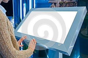 Woman using interactive empty white touchscreen display kiosk at exhibition