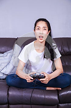 Woman using joystick controller playing video game on sofa in li