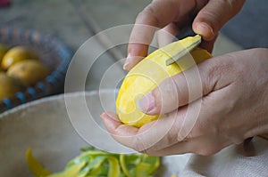 Woman using a knife to peel ripe mango. The local fruits are sweet