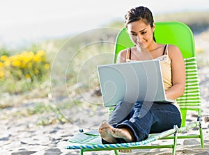 Woman using laptop at beach