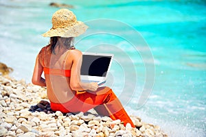 Woman using laptop on the beach