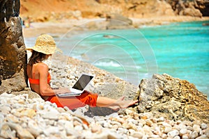 Woman using laptop on the beach