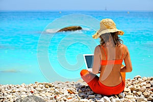 Woman using laptop on the beach