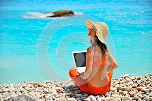 Woman using laptop on the beach