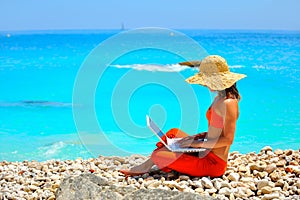 Woman using laptop on the beach