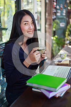 Woman using laptop at cafe while drinking coffee