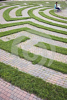 Woman Using Laptop in a Cobblestone Maze