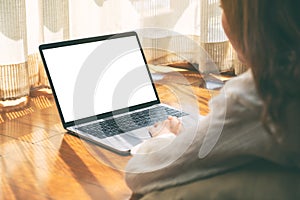 A woman using laptop computer with blank white desktop screen while laying down on the floor with feeling relaxed