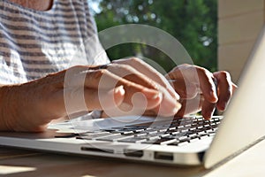 Woman using a laptop computer, close-up of hands