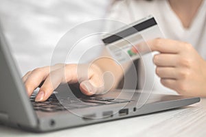 Woman using laptop computer with credit card in hand. Concept of online shopping, spending money and e-commerce