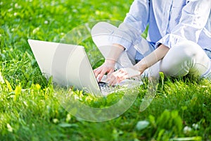 Woman using laptop computer on green grass